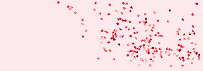 scattered pink holographic glitter confetti star shaped on candy pink background top view copy space. Festive holiday pastel backdrop. Birthday, giveaway, Christmas, New Year. Mothers Day banner