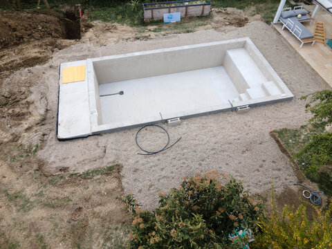 Drone photo of swimming pool in construction phase with gravel all around in a garden