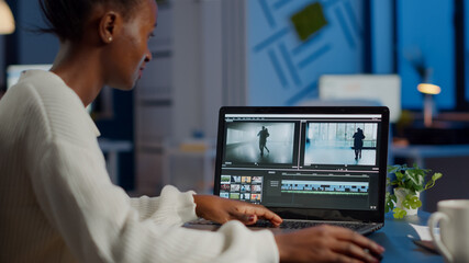 African videographer working at laptop from business office, editing video and audio footage at...