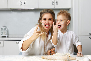 Funny mom and son smeared in flour and show their hands the sign of rock and roll