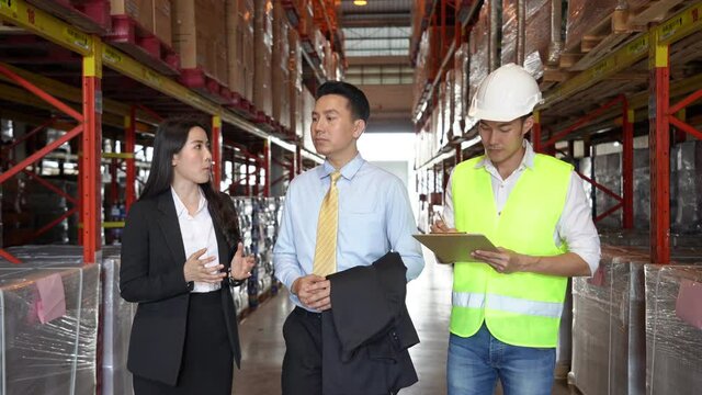 Group of Asian business people and warehouse worker discussion business project using digital tablet in distribution fulfillment center. eCommerce, B2B business, factory industry logistic concept.