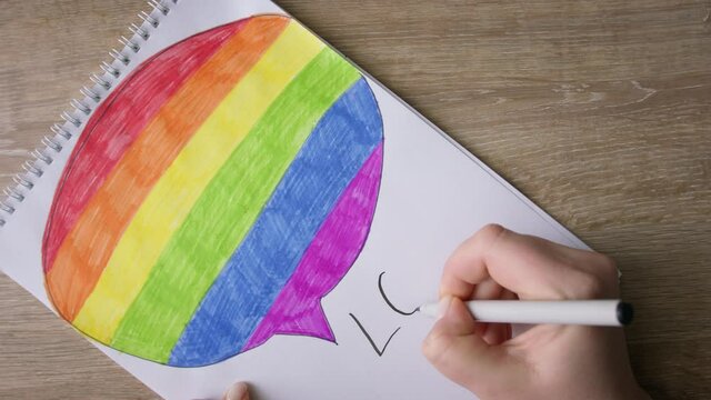 Female hands write down LOVE WINS on drawing with rainbow colors element.