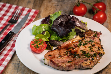 Recipe for grilled pork chop, maple syrup and fresh cilantro marinade, parsley, garlic, served with a salad.