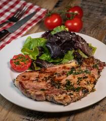 Recipe for grilled pork chop, maple syrup and fresh cilantro marinade, parsley, garlic, served with a salad.
