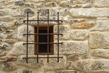 Rustic wrought iron window on a stone facade. 