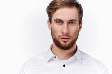 blond man with a thick beard and mustache in a white shirt on a light background