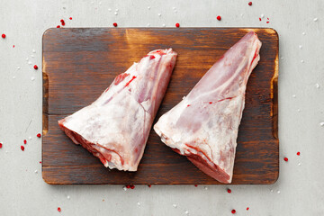 Raw lamb shanks on wooden board close up