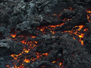 Closeup view of cooling down lava rocks with orange glow after the eruption of a volcano in...