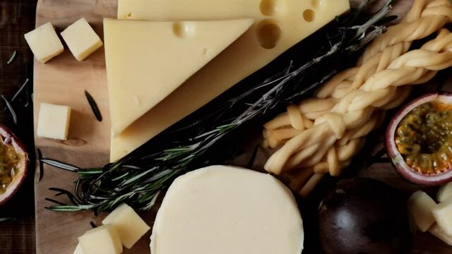 Cheese platter. Cheese board. Mazdamer cheese, gouda, soft cheese, smoked cheese and passionfruit fruit in a cut on a wooden board on a wooden table.Cheese specialties on wood surface.Cheese platter w