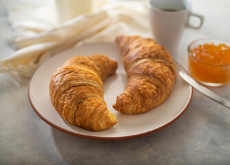Croissants with coffee and orange jam on a light table. Breakfast at the hotel