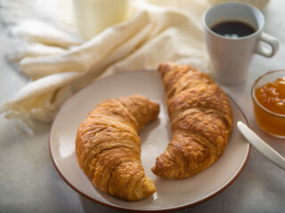Croissants with coffee and orange jam on a light table. Breakfast at the hotel