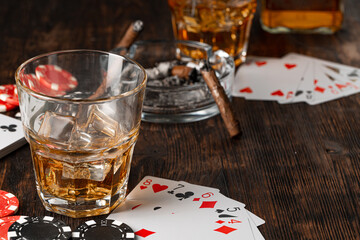 Playing poker with whiskey and cigars on table