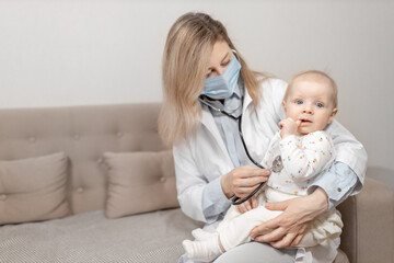 Fototapeta na wymiar Woman doctor in blue mask doing a month checkup of little girl hold a stethoscope. Female pediatrician examining cute toddler, checks heart and lungs of adorable baby. Health care concept