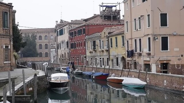 edifici storici veneziani con vista sulla canale insieme alle barche parcheggiate 