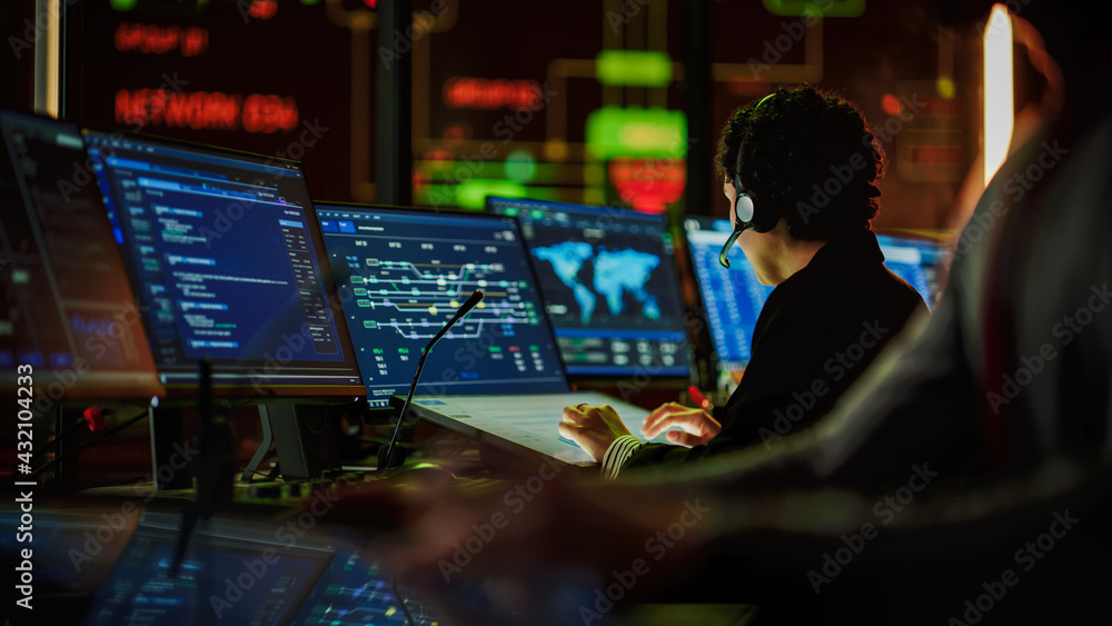 Aufkleber Multiethnic Female IT Technical Support Specialist Talking with a Client in Headphones and Working on Desktop Computer in Monitoring Control Room with Big Digital Screens with Server Blockchain Data.