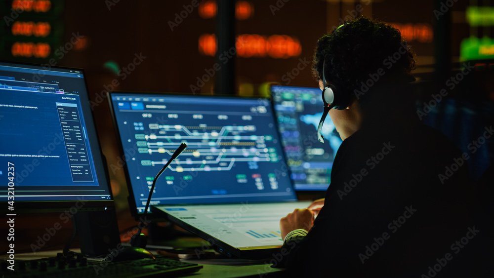 Poster Multiethnic Female IT Technical Support Specialist Talking with a Client in Headphones and Working on Desktop Computer in Monitoring Control Room with Big Digital Screens with Server Blockchain Data.