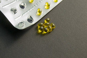 Yellow pills on a black background. next to an empty blister. treatment and prevention of diseases....