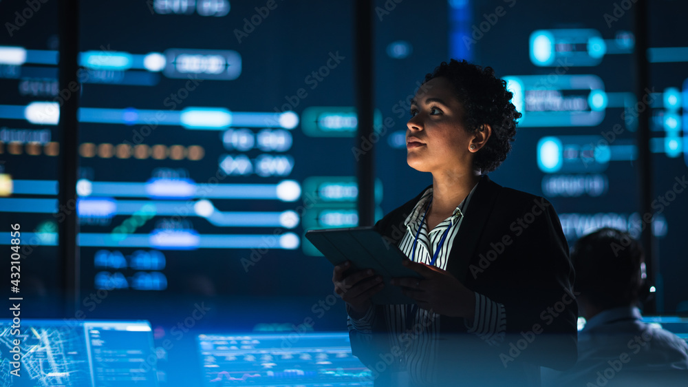 Leinwandbilder young multiethnic female government employee uses tablet computer in system control monitoring cente