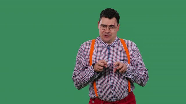 The man portrays a cat, whines. Portrait of a man in glasses, a plaid shirt with orange suspenders in the studio on a green screen. Slow motion. Close up.