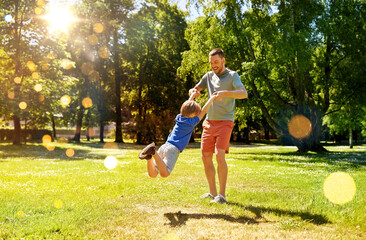 Fototapeta premium family, fatherhood and people concept - happy father with little son playing in summer park