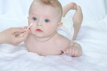 The mother applies the medicated ointment to the baby's cheek. Copy space - baby face clean and...