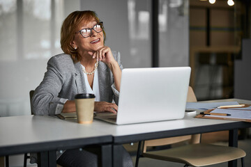 Joyful businesswoman giving a smile to laptop screen during meeting