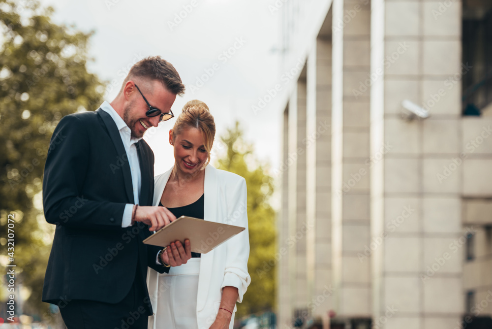 Wall mural Two happy businesspeople using a digital tablet