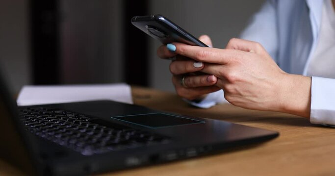 Anonymous Businesswoman holding in hands smartphone, typing text message via cell phone, charging in mobile phone, using modern device, freelancer woman working at home or office