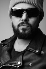 Vertical black and white portrait of handsome bearded man, wearing pink hat.