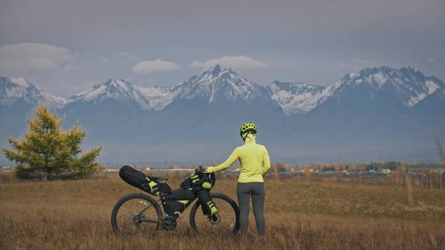 The woman travel on mixed terrain cycle touring with bikepacking. The traveler journey with bicycle bags. Sport tourism bikepacking.
