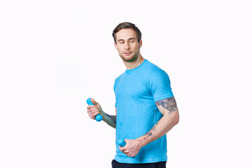a man doing exercises with dumbbells on a light background in a blue t-shirt and pants