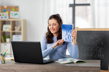 distant education, primary school and teaching concept - female math teacher with laptop computer...