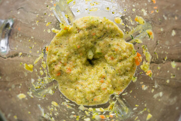 Blender in the process of grinding vegetables on a wooden table, top view.Healthy and correct nutrition