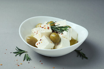 Bowl with feta cheese and spices on gray background