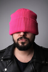 Vertical close-up portrait of young handsome bearded man, wearing pink hat.