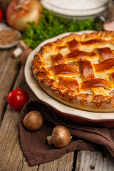 Pie with meat and mushrooms on a wooden table with ingredients