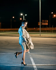 Young girl in a parking lot against the backdrop of the night city