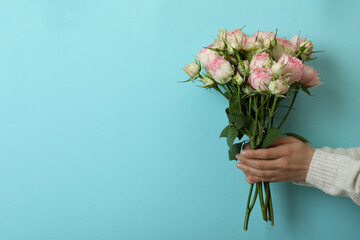 Female hands hold roses on blue background