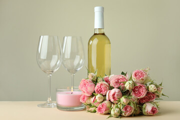 Romantic concept with roses, wine and candle on beige table