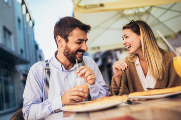 Young happy couple eating pizza for lunch in a restaurant