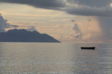 Seascape.Lonely fishing boat in the sea in the morning at sunrise with an island on the...