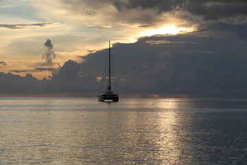Silhouette of a sailboat at sea on shimmering silvery water at sunset of the day. A beautiful image...