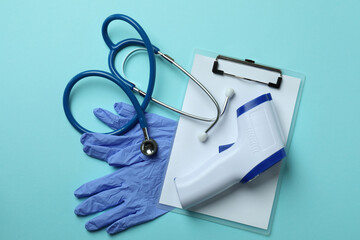 Medical tools and thermometer gun on blue background