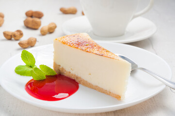 homemade cheesecake on a white plate with strawberry sauce