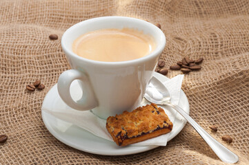 a Cup of coffee with coffee beans on a sackcloth with cookies