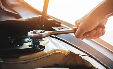 Mechanic hand is unscrewing to nut of the car with the socket wrench