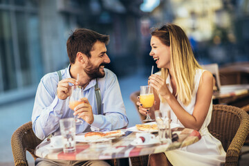 Young happy couple eating pizza for lunch in a restaurant