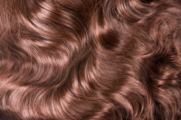 Brown hair texture. Wavy long curly light brown hair close up as background. Hair extensions, materials and cosmetics, hair care. Hairstyle, haircut or dying in salon.
