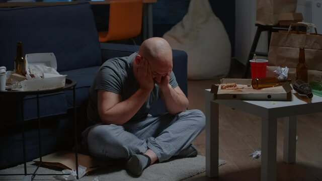 Desperate hopeless man sitting alone on floor swaying having suicide thoughts chronic disease feeling depressed, upset stressed. Worried person suffering from anxiety, loneliness mental health problem