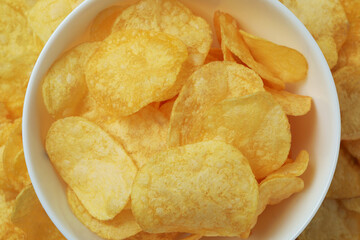 Bowl with tasty potato chips, top view